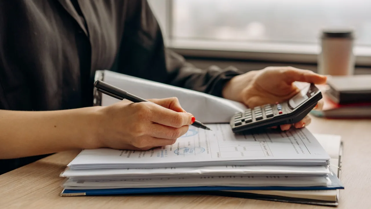 A calculator and pen resting on printed financial documents on a desk