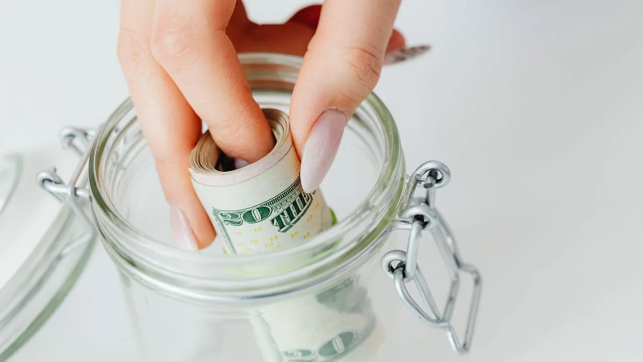 A glass jar filling with cash and coins as an emergency fund