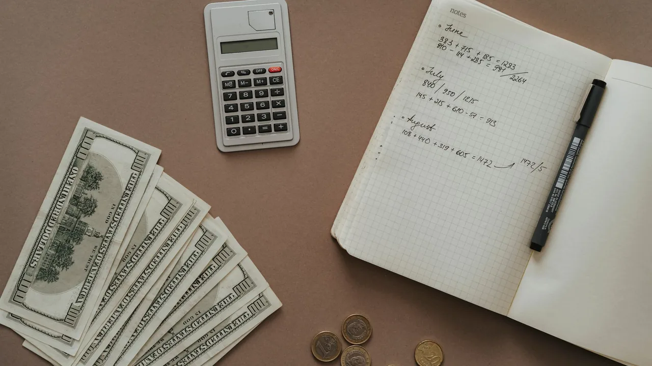 Cash, coins and a calculator on a desk, representing money and the cost of living